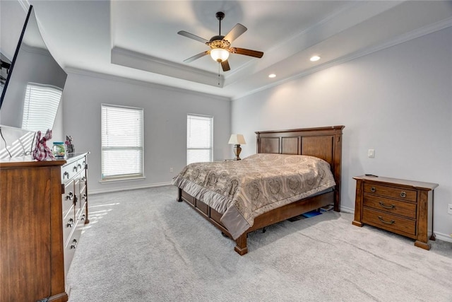 bedroom with ceiling fan, a raised ceiling, crown molding, and light carpet