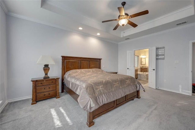 carpeted bedroom with ensuite bath, a raised ceiling, ceiling fan, and crown molding