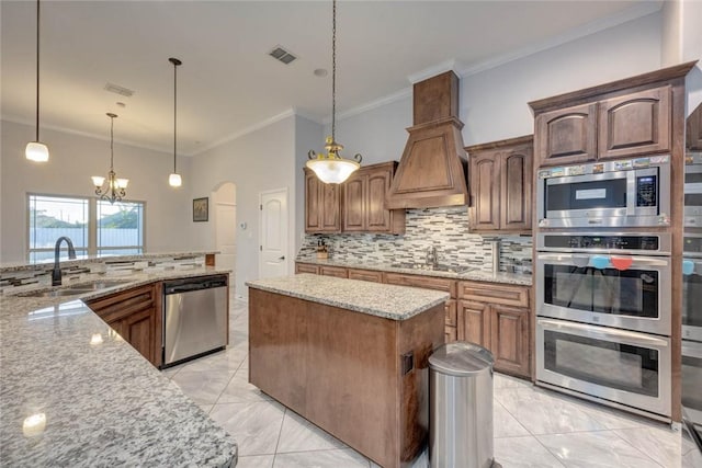 kitchen featuring light stone counters, decorative light fixtures, decorative backsplash, a kitchen island, and appliances with stainless steel finishes