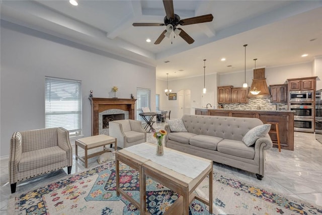 living room featuring beam ceiling, ceiling fan with notable chandelier, and sink