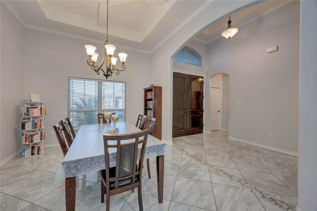 dining area featuring a chandelier, a tray ceiling, and ornamental molding