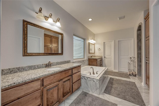 bathroom featuring vanity and a relaxing tiled tub