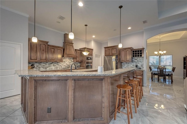 kitchen featuring backsplash, an inviting chandelier, hanging light fixtures, light stone countertops, and stainless steel appliances