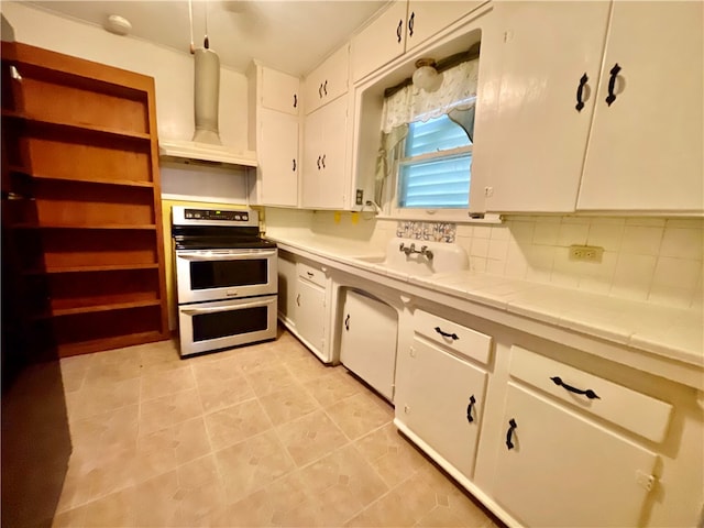 kitchen with electric stove, hanging light fixtures, tasteful backsplash, custom exhaust hood, and white cabinetry