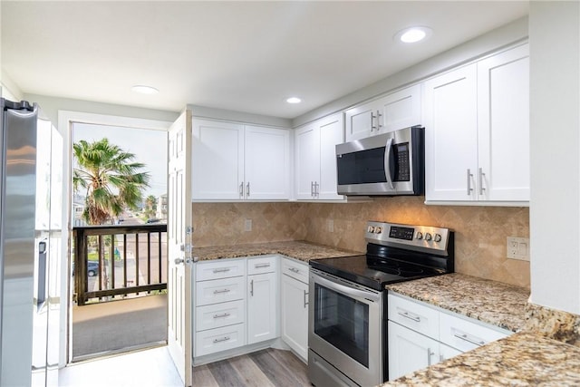200 W Cotter Ave Unit B-3, Port Aransas, TX 78373 - kitchen with appliances with stainless steel finishes, white cabinets, light stone countertops, light wood finished floors, and backsplash