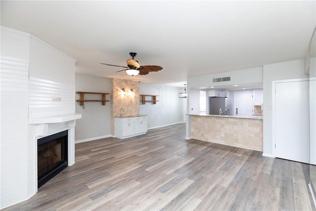 200 W Cotter Ave Unit B-3, Port Aransas, TX 78373 - unfurnished living room featuring a fireplace, ceiling fan, light wood finished floors, and baseboards