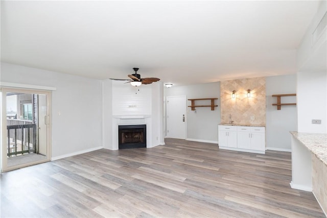 200 W Cotter Ave Unit B-3, Port Aransas, TX 78373 - unfurnished living room featuring a ceiling fan, light wood finished floors, a fireplace, and baseboards