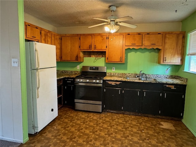 kitchen with gas range, a textured ceiling, sink, ceiling fan, and white fridge