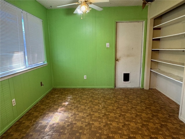 unfurnished room featuring dark parquet floors, ceiling fan, and a textured ceiling