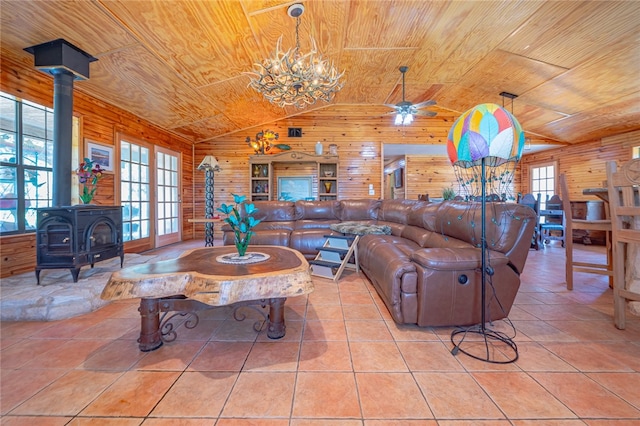 tiled living room featuring a wood stove, wood walls, a healthy amount of sunlight, and wooden ceiling