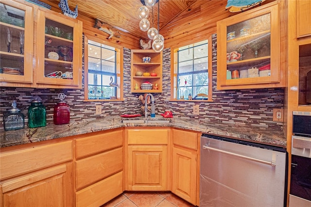 kitchen with stainless steel dishwasher, light stone counters, light tile patterned floors, and plenty of natural light