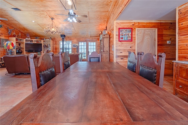 dining area with wood walls and ceiling fan with notable chandelier