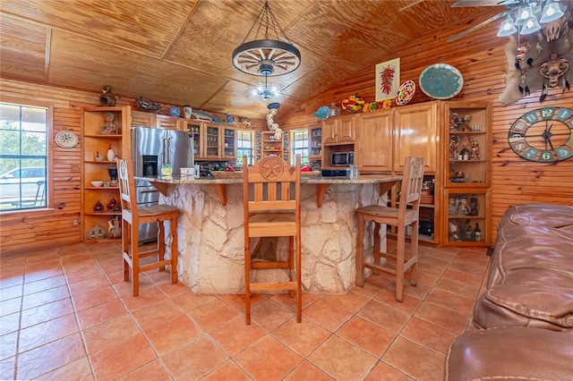 kitchen with wooden ceiling, ceiling fan, wood walls, and appliances with stainless steel finishes