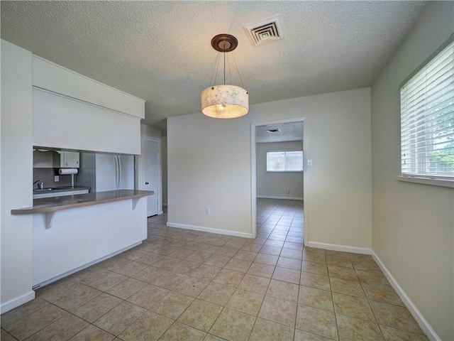 1638 Spicewood Dr, Corpus Christi, TX 78412 - kitchen with a textured ceiling, a breakfast bar, light tile patterned floors, decorative light fixtures, and a peninsula