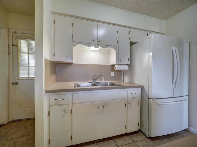 1638 Spicewood Dr, Corpus Christi, TX 78412 - kitchen featuring freestanding refrigerator, light tile patterned floors, light countertops, and white cabinetry