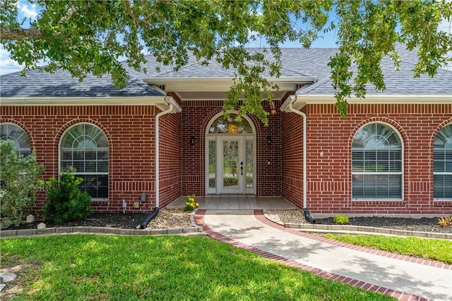 7526 Milan St, Corpus Christi, TX 78414 - property entrance featuring french doors, brick siding, roof with shingles, and a lawn