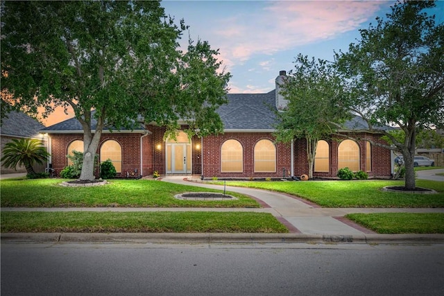 7526 Milan St, Corpus Christi, TX 78414 - view of front of home featuring a lawn, a chimney, brick siding, and a shingled roof
