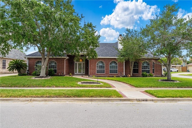 7526 Milan St, Corpus Christi, TX 78414 - view of front of property with french doors, a front lawn, brick siding, and a chimney
