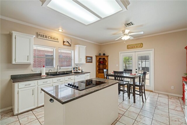 7526 Milan St, Corpus Christi, TX 78414 - kitchen featuring black electric stovetop, light marble finish flooring, a ceiling fan, white cabinets, and crown molding