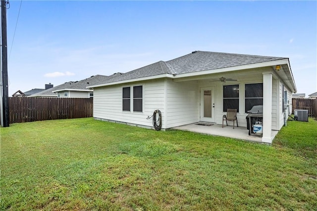 rear view of house with a shingled roof, a patio area, central AC, a ceiling fan, and a lawn