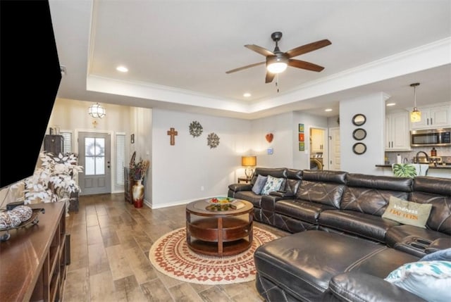 living room with baseboards, recessed lighting, a raised ceiling, and a ceiling fan