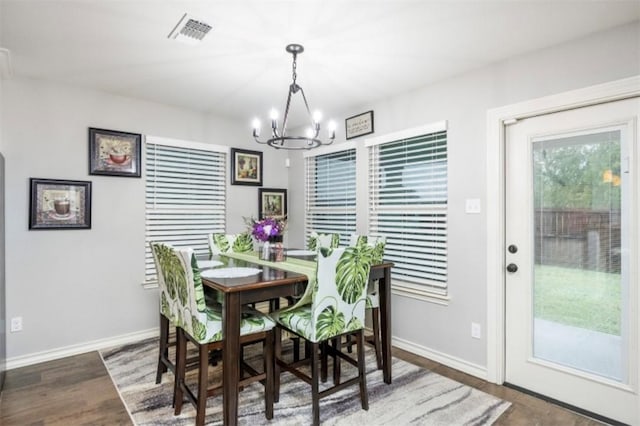 dining area featuring wood finished floors, visible vents, a notable chandelier, and baseboards