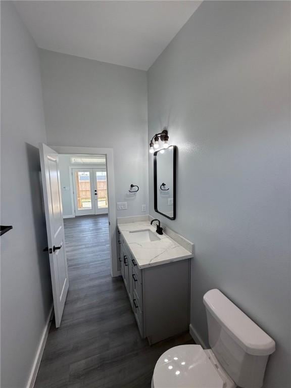 bathroom featuring wood-type flooring, toilet, vanity, and french doors