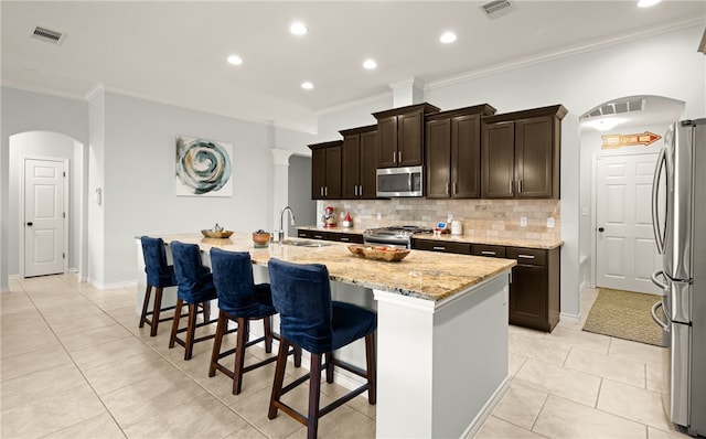 kitchen with appliances with stainless steel finishes, tasteful backsplash, crown molding, sink, and an island with sink