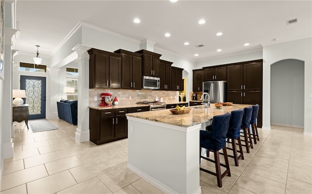 kitchen with a kitchen breakfast bar, a spacious island, light stone countertops, ornamental molding, and stainless steel appliances