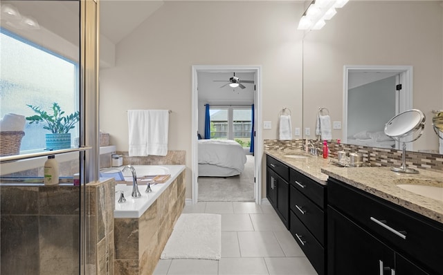 bathroom featuring vanity, tile patterned floors, vaulted ceiling, ceiling fan, and tiled tub