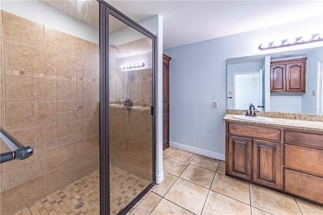 bathroom featuring a stall shower, tile patterned floors, baseboards, and vanity