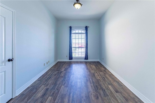 empty room with baseboards and dark wood-type flooring