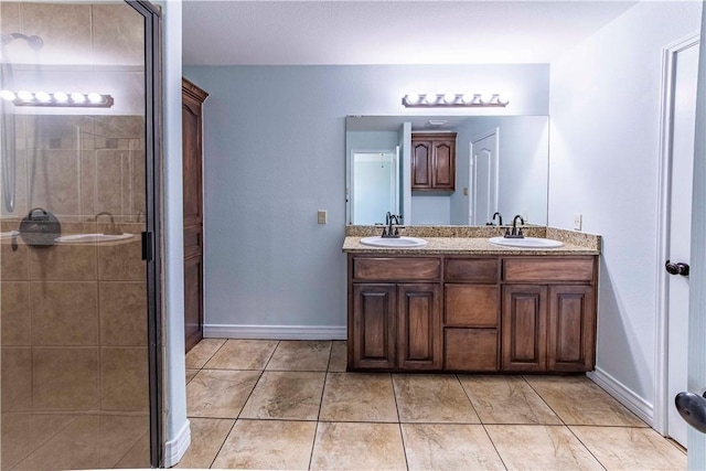 full bathroom featuring a stall shower, a sink, baseboards, and double vanity