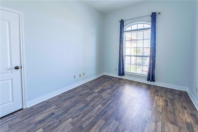 spare room featuring a healthy amount of sunlight, baseboards, and dark wood-style flooring