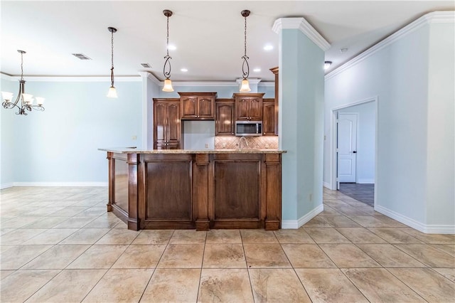 kitchen featuring decorative backsplash, an island with sink, ornamental molding, appliances with stainless steel finishes, and hanging light fixtures