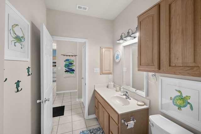 bathroom with toilet, vanity, and tile patterned flooring