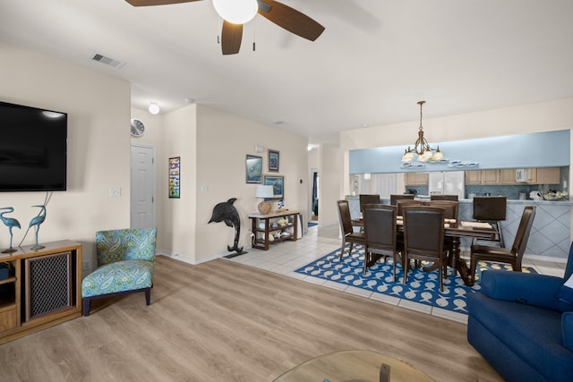 dining area featuring ceiling fan with notable chandelier and light hardwood / wood-style flooring