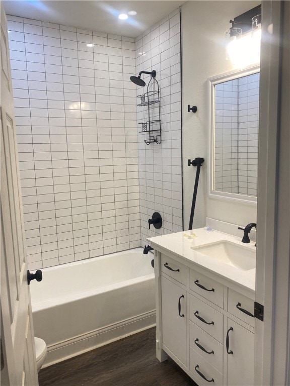 full bathroom featuring toilet, tiled shower / bath combo, vanity, and hardwood / wood-style flooring