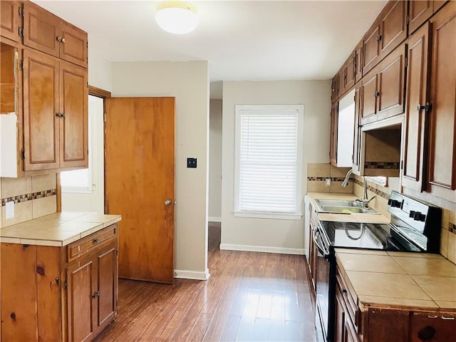 912 E Fulton St, Sinton, TX 78387 - kitchen featuring electric range, a sink, tile countertops, tasteful backsplash, and baseboards