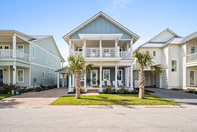 view of front of home with a balcony, a porch, and a front lawn