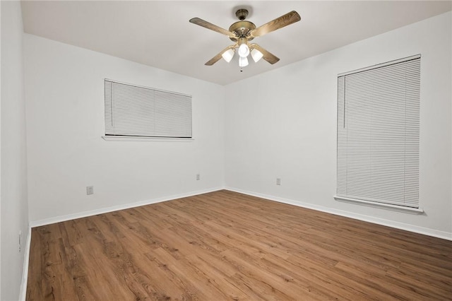empty room with wood finished floors, ceiling fan, and baseboards