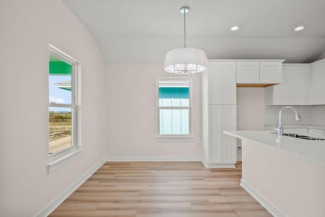 kitchen featuring light hardwood / wood-style floors, light stone countertops, sink, and white cabinets