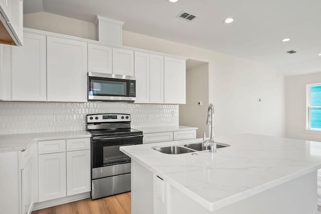 kitchen with stainless steel appliances, a kitchen island with sink, sink, and white cabinets