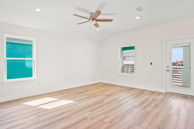 spare room with lofted ceiling, a wealth of natural light, ceiling fan, and light wood-type flooring