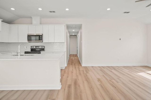 kitchen with appliances with stainless steel finishes, tasteful backsplash, white cabinetry, sink, and light hardwood / wood-style floors