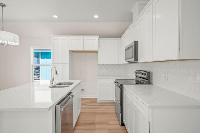 kitchen featuring sink, a center island with sink, appliances with stainless steel finishes, pendant lighting, and white cabinets