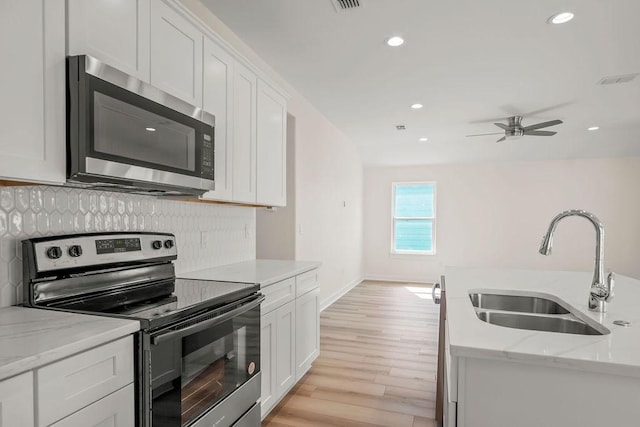 kitchen with white cabinetry, sink, light stone counters, and stainless steel appliances