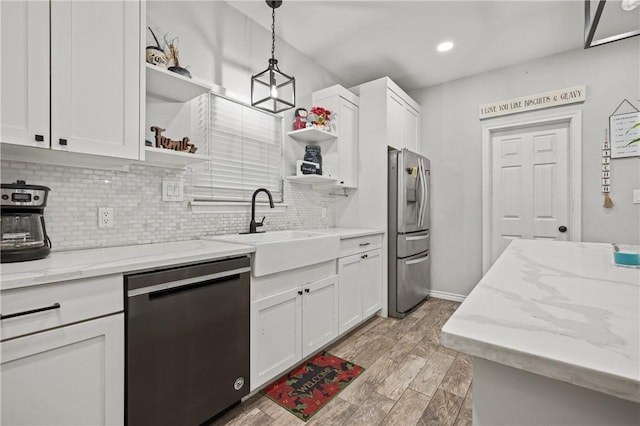 kitchen featuring hanging light fixtures, white cabinets, stainless steel appliances, and sink