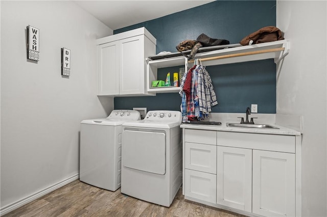 washroom with cabinets, light hardwood / wood-style floors, washer and clothes dryer, and sink