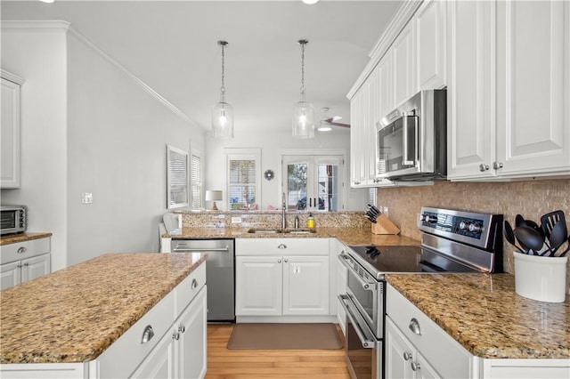 kitchen with decorative light fixtures, sink, white cabinets, kitchen peninsula, and stainless steel appliances